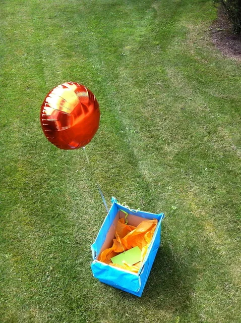 Coffret cadeau ouvert : un ballon s'envole, l'enveloppe avec les billets reste au fond de la boîte